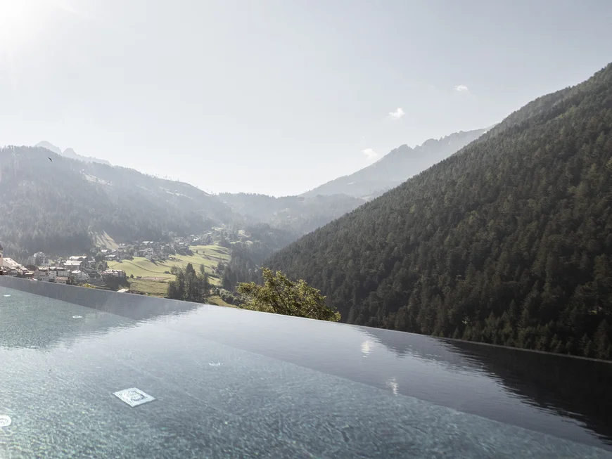 Friedrich ist DAS Boutiquehotel in den Dolomiten Infinity-Pool mit Bergblick und Sonnenschein an einem klaren Tag