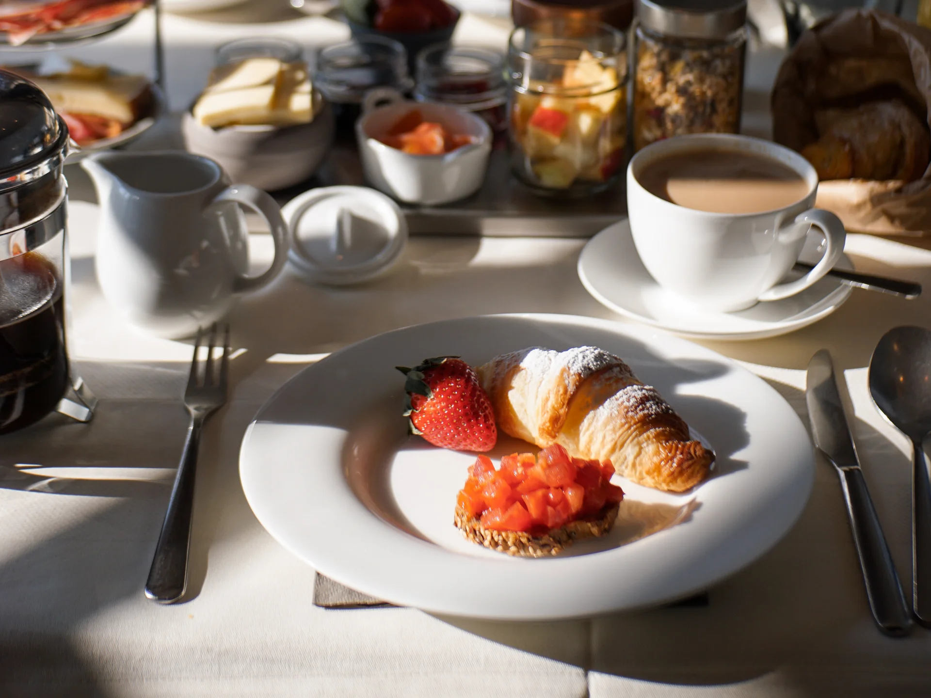 Friedrich ist DAS Boutiquehotel in den Dolomiten Tisch mit Frühstück: Croissant, Erdbeere, Kaffee, Marmelade und Frühstückszutaten