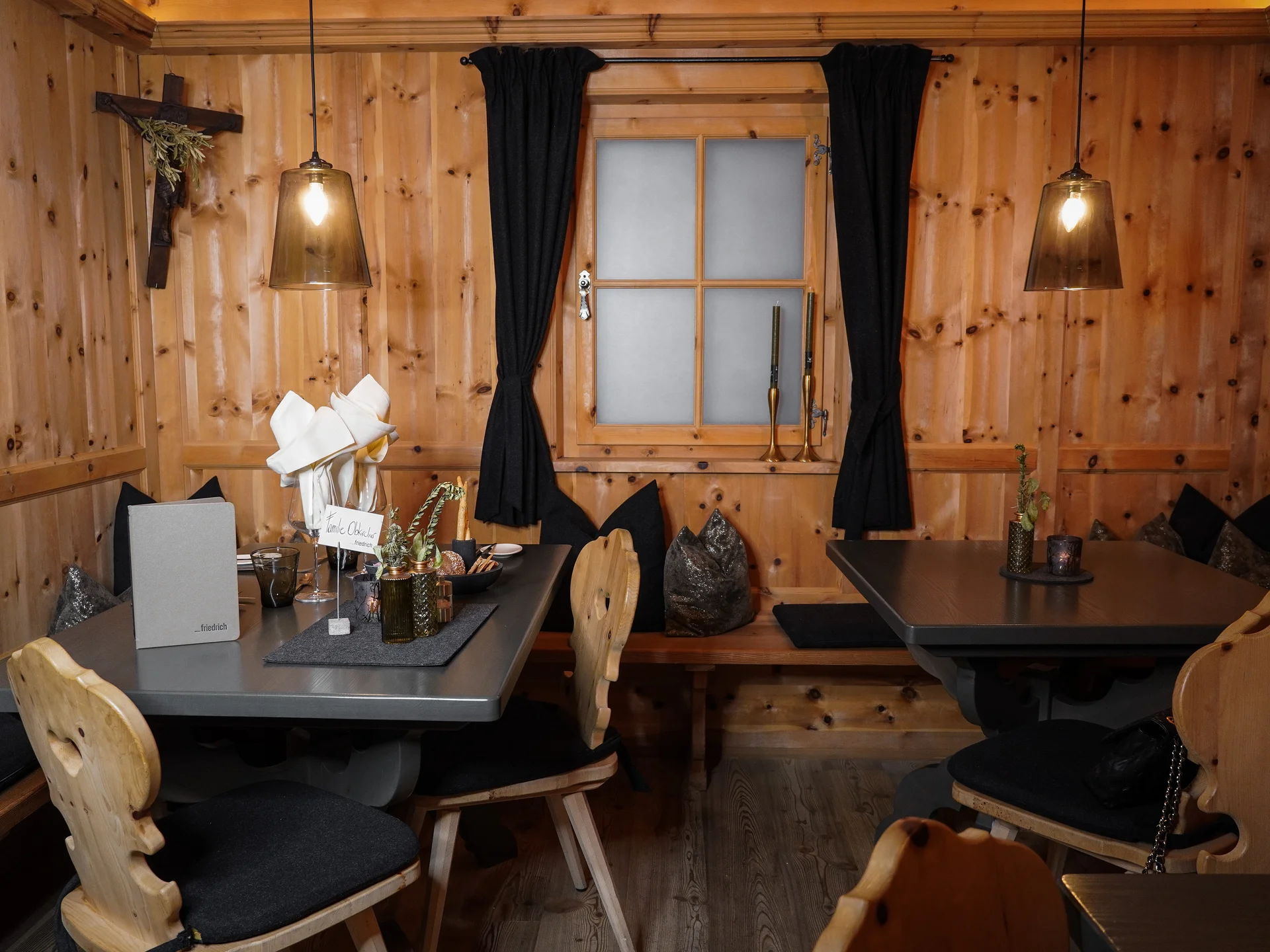 Friedrich ist DAS Boutiquehotel in den Dolomiten Gemütlicher Gastraum mit Holztischen, Stühlen und schwarzer Dekoration