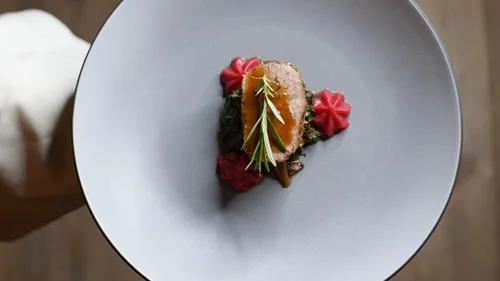 Friedrich ist DAS Boutiquehotel in den Dolomiten Elegante Speise mit Fleisch, Soße und Rosmarin auf grauem Teller