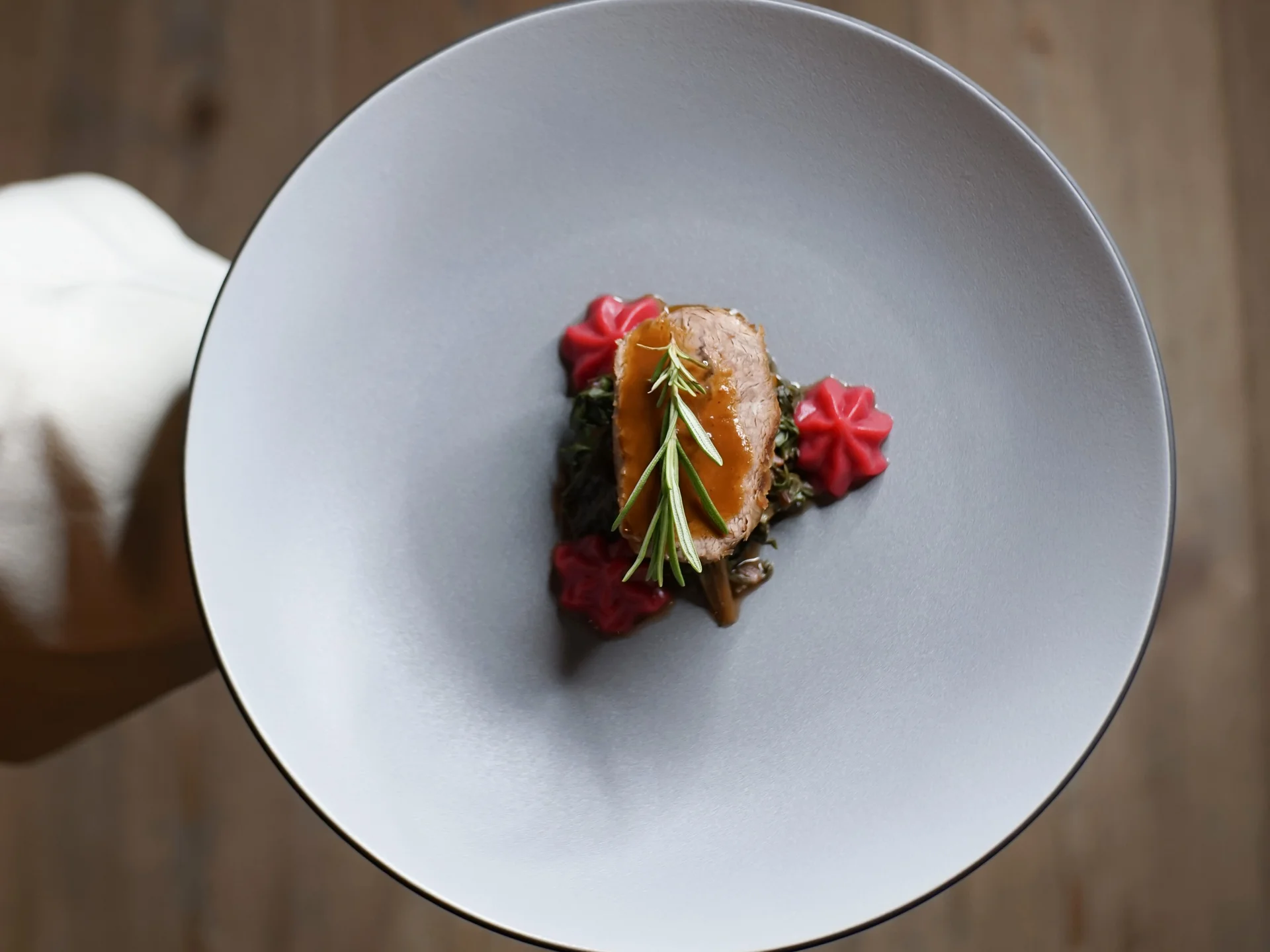 Friedrich ist DAS Boutiquehotel in den Dolomiten Elegante Speise mit Fleisch, Soße und Rosmarin auf grauem Teller